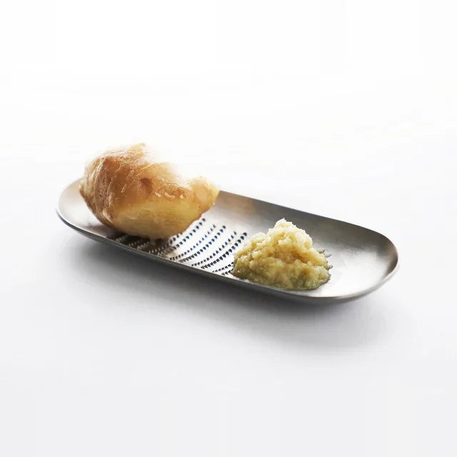 Oros grater with grated toppings on a white table