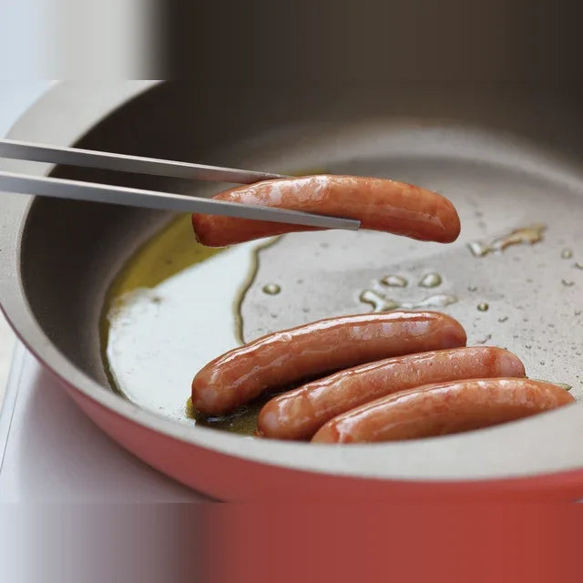 Saibashi tongs turning sausages in a pan