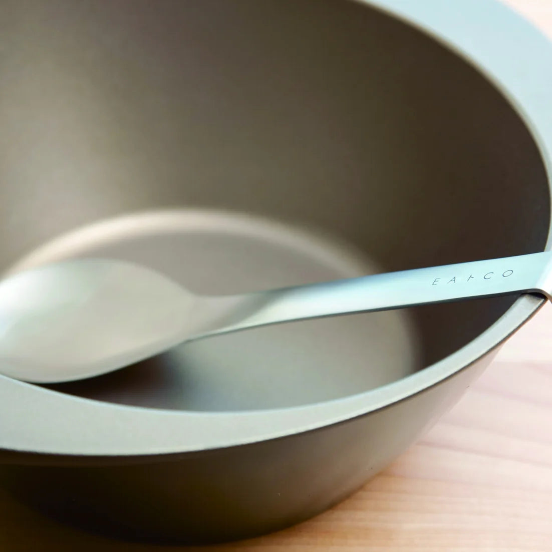 Suqu stainless serving spoon resting on the rim of a pot