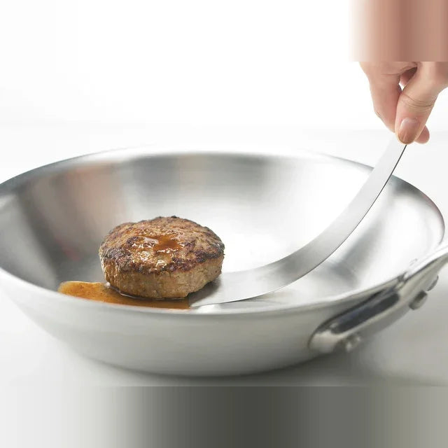 Tolu spatula lifting a hamburg steak from a frying pan