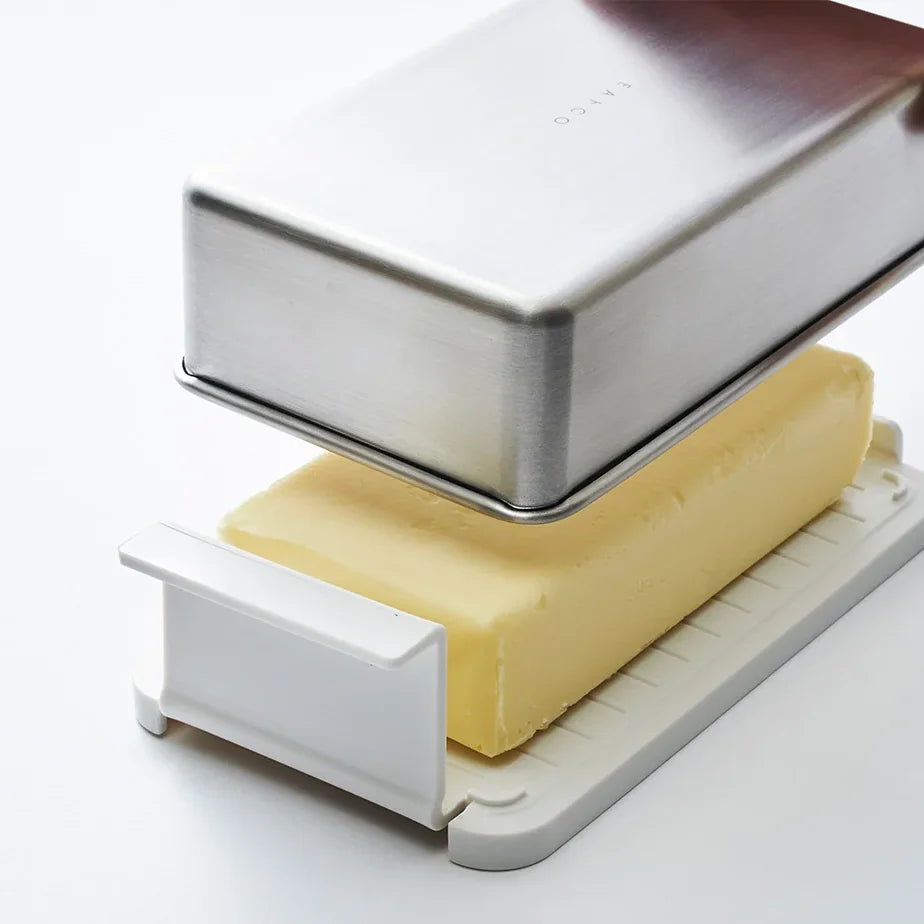 Stainless butter case with the lid lifted over a block of butter