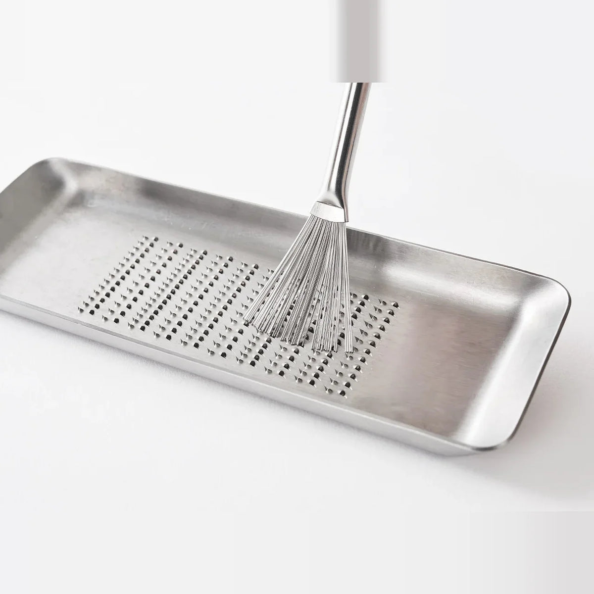 Hake grater brush on a stainless grater tray
