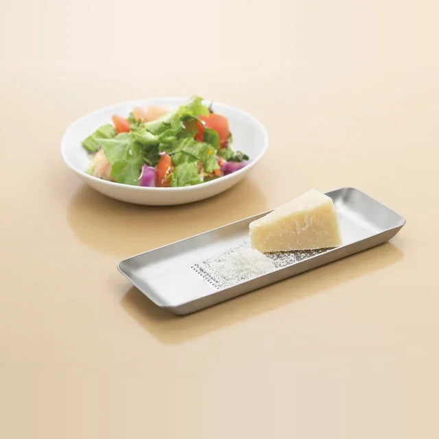 Oros grater with a block of cheese next to a salad