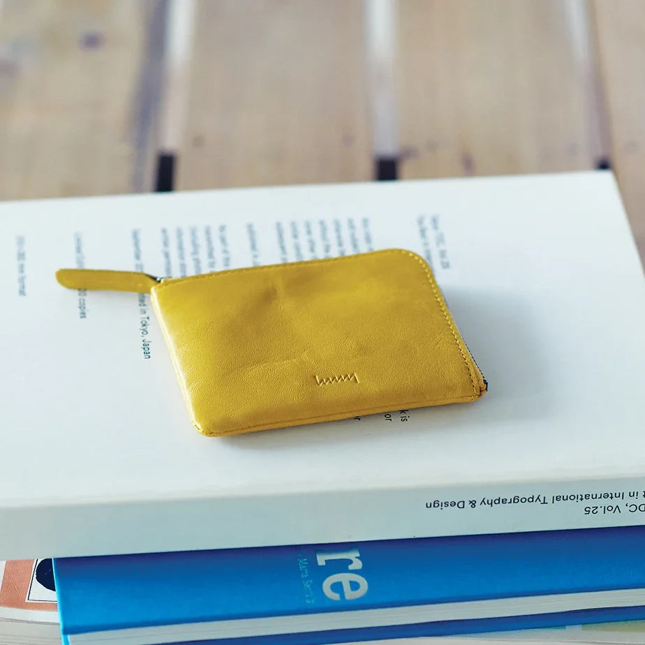 Yellow hmny compact wallet on a stack of books