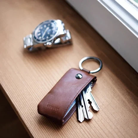 Brown hmny key case with keys and a watch