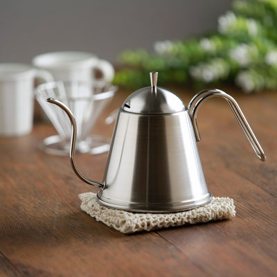 Stainless steel ITTEKI drip pot on a wooden table with coffee cups