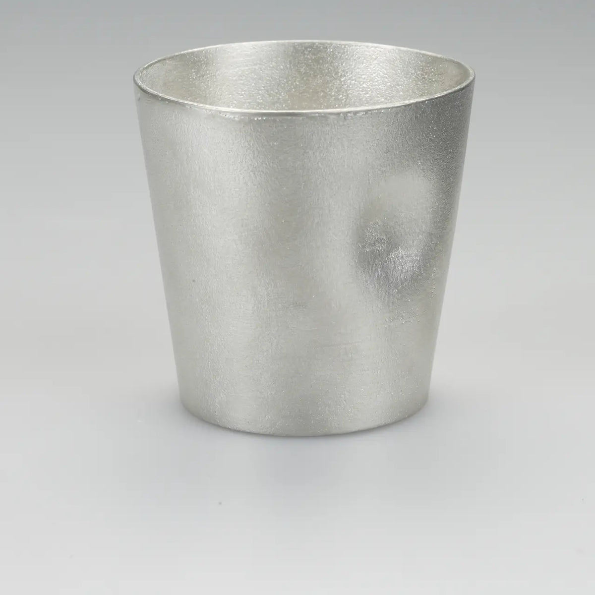 Single NAJIMI tin tumbler with thumb hollow on a gray background