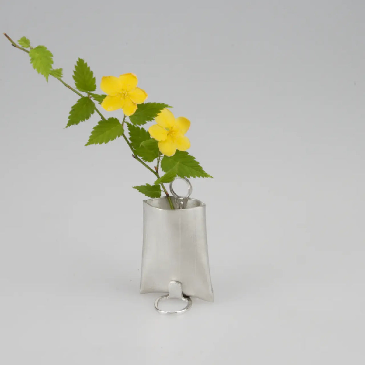 Suzuhana tin bud vase holding a yellow flower
