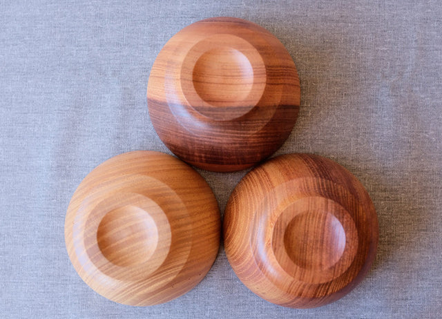 Bottoms of three ISHIZUE bowls showing different wood grain