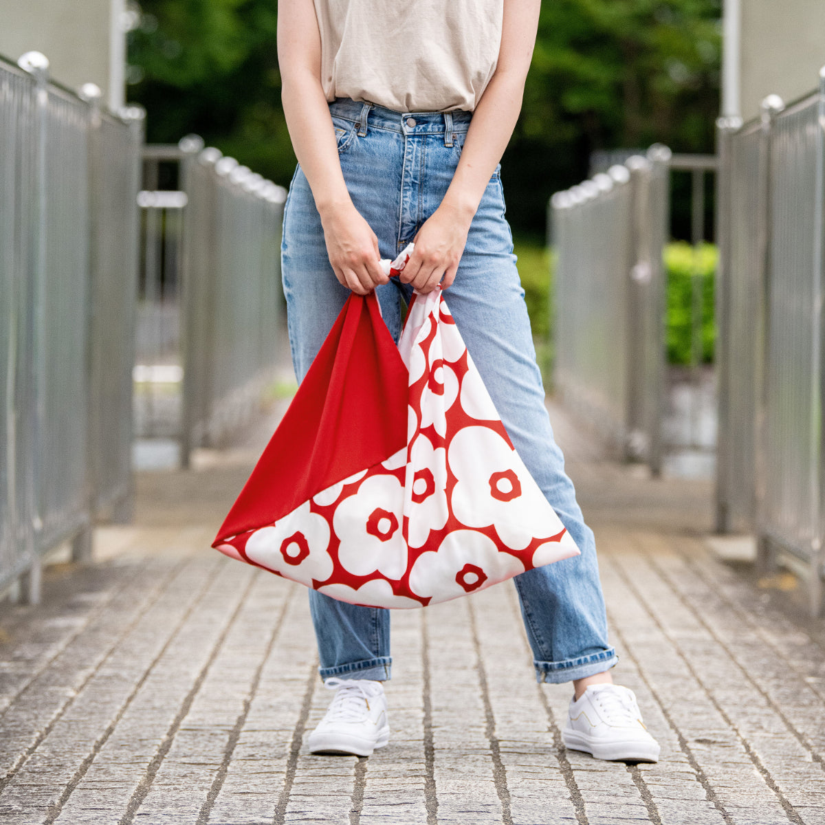 Woman holding the AZUMA bag in Camellia Red by its handles #Pattern_Camellia Red