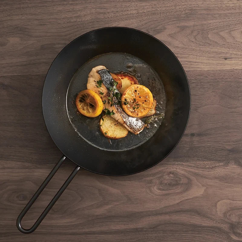 Tetsu Pan iron frying pan with grilled fish and vegetables on a wooden table