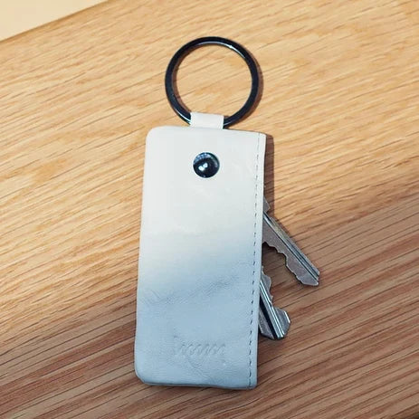 Light gray hmny key case on a wooden table