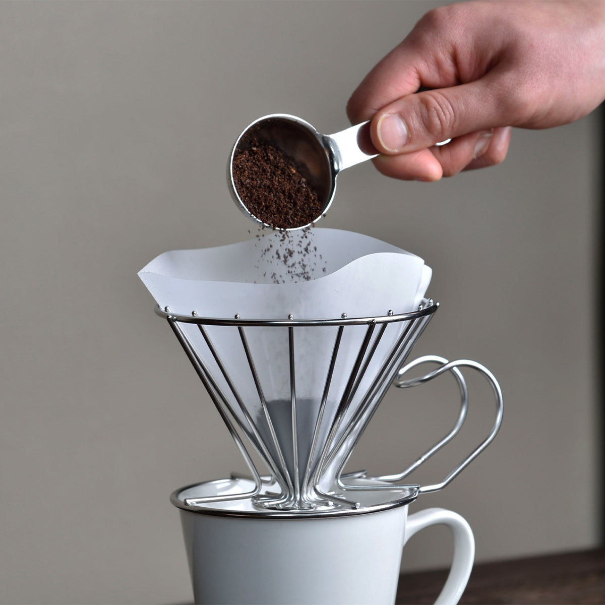 Adding ground coffee to a dripper with the 10g measure