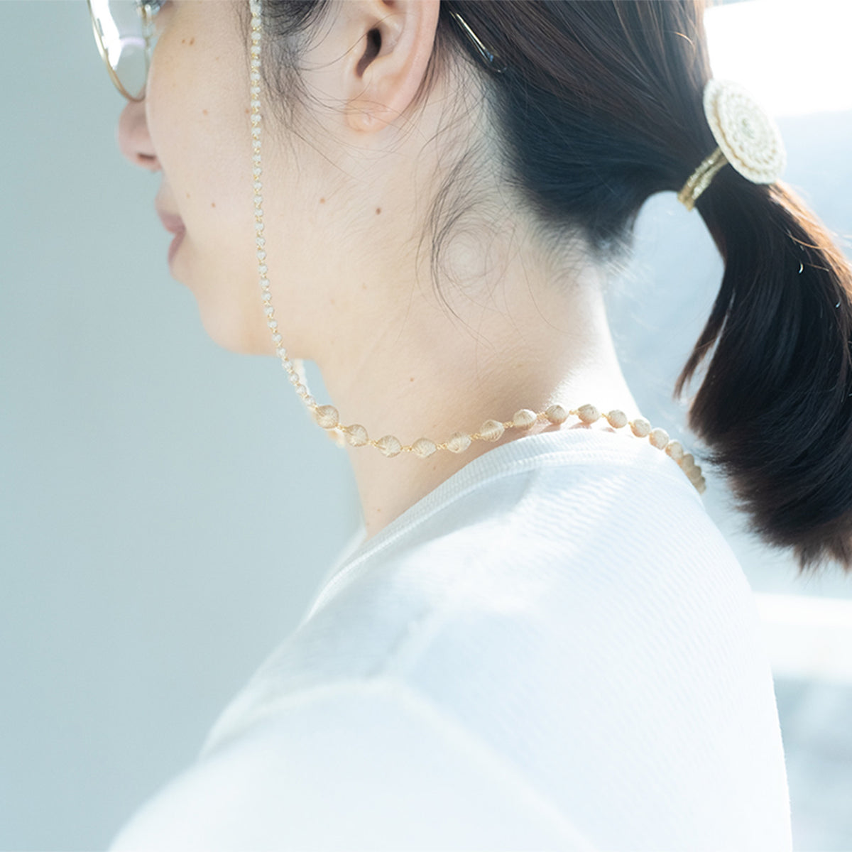 Woman wearing a beaded glasses cord, side view