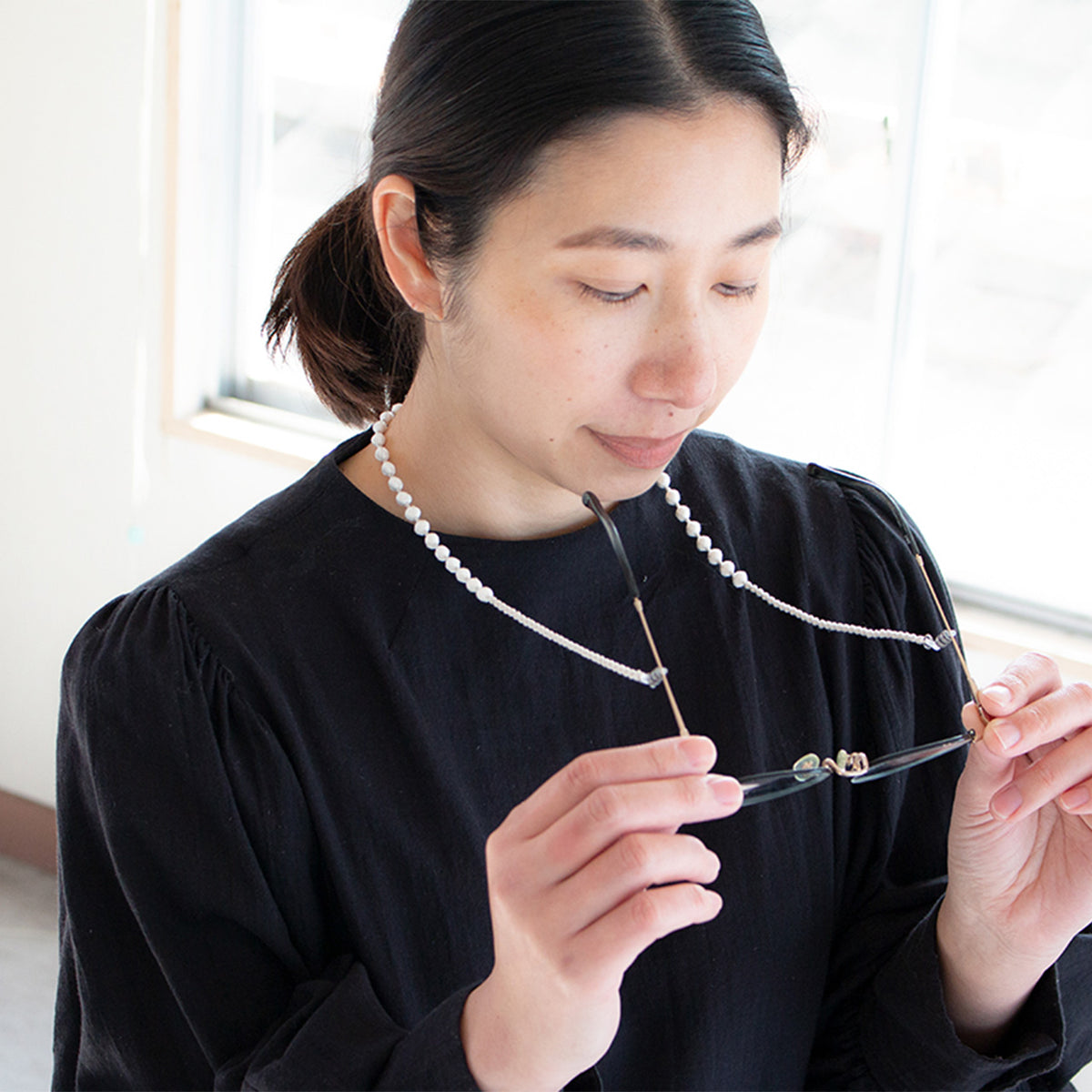 Woman holding her glasses on the beaded cord