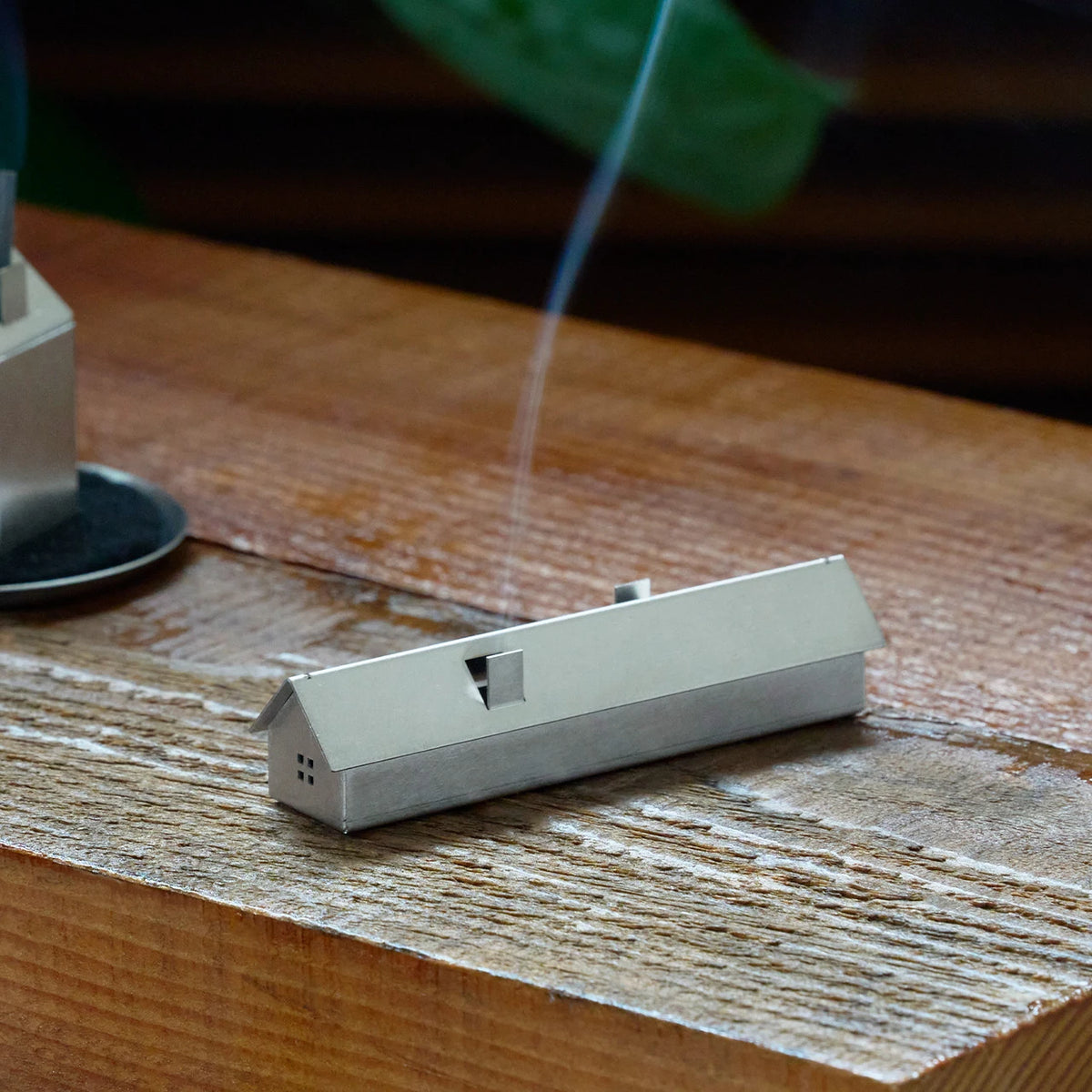 Stainless steel Incense House with a thin line of smoke from its chimney