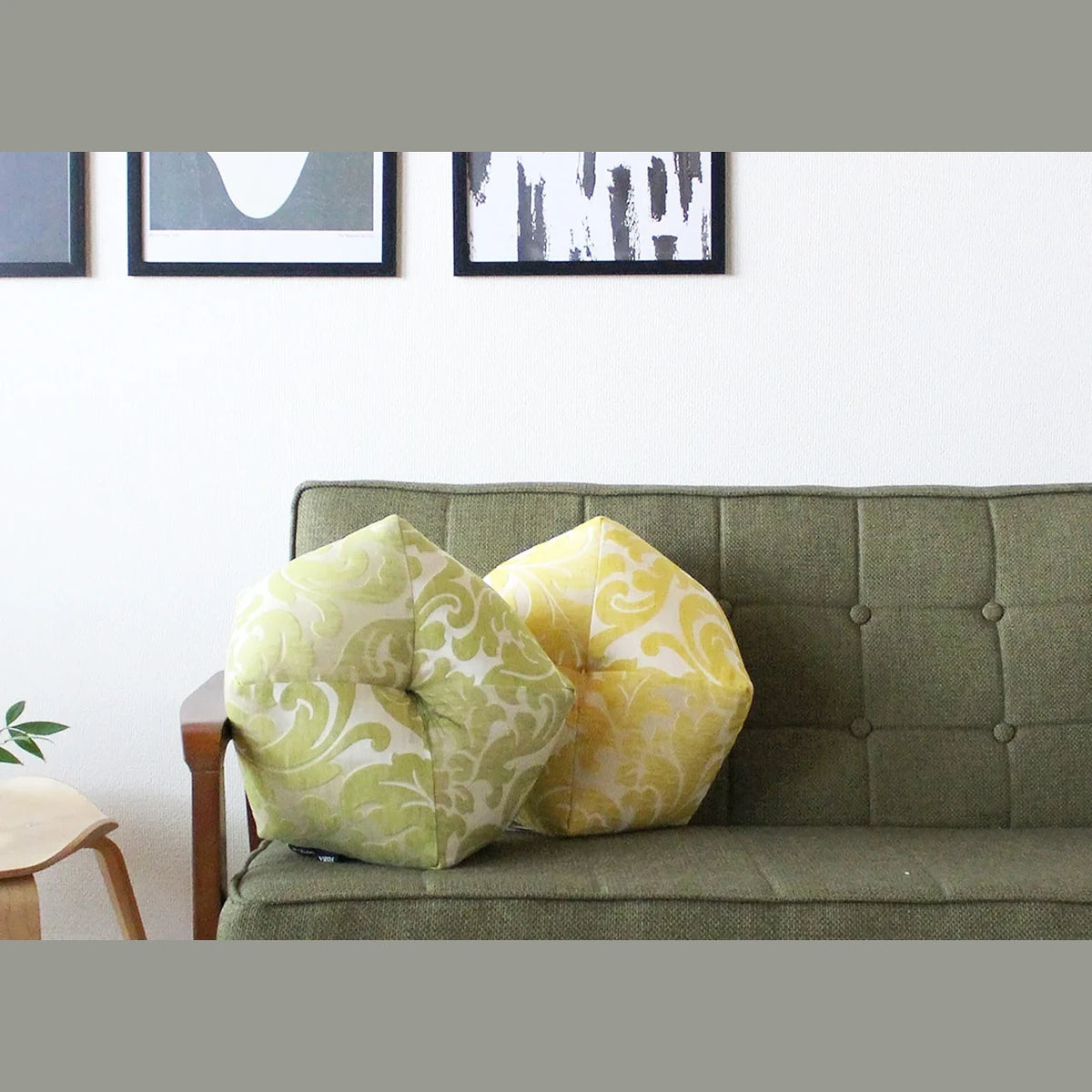 Ojami cushions Fisba Nouvelle on a green sofa